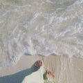 Low angle and closeup of a girls feet standing on wet sand at the beach Royalty Free Stock Photo