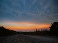 LOW ANGLE: Dark mammatus clouds gather above an empty gravel road in countryside