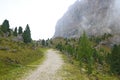 Low-angle of a dusty road leading to the peaks of the Dolomites covered with fog