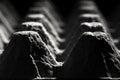 Low angle, extreme close up of an empty cardboard egg tray. Dark mooded, abstract, monochromatic image of the texture and pattern