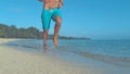 LOW ANGLE: Fit young man on summer vacation runs down the empty white sand beach