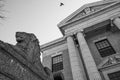 Low angle grayscale of a beautiful sculpture of a majestic male lion outside a classical building