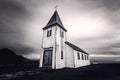 Low angle grayscale shot of the Hellnar Church in a field in Iceland on a cloudy day