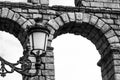 Low angle grayscale shot of a street lamp near an old stone bridge
