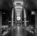 Low angle grayscale view of a modern building hall with a clock hanging from the ceiling