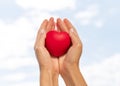 low angle hands holding heart shape with sky. High quality photo