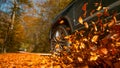 LOW ANGLE: Large 4x4 vehicle drives along a road full of brown fallen leaves.