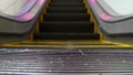 Low angle looped perspective view of modern escalator stairs. Automated elevator mechanism. Yellow line on stairway illuminated Royalty Free Stock Photo