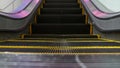 Low angle looped perspective view of modern escalator stairs. Automated elevator mechanism. Yellow line on stairway illuminated Royalty Free Stock Photo