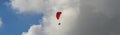 Low angle panorama of a paraglider under the sunlight and a cloudy sky at daytime