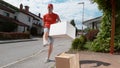 LOW ANGLE: Parcel delivery guy drop kicks a package into someone's driveway.