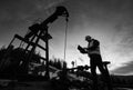 Oil man controlling work of petroleum pump jack. Royalty Free Stock Photo