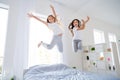 Low angle photo of cheerful kids jumping bed have free time raise hands feel content room indoors apartment