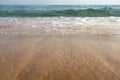 Low angle photo from ground level - beach sand wet from sea, drops of water in air, small waves and blurred ocean in distance. Ab Royalty Free Stock Photo