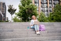 Low angle photo of student young woman blonde sits upstairs near university campus and doing homework using laptop bring Royalty Free Stock Photo