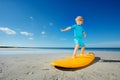 Low angle portrait of blond boy stand on the surfboard at beach Royalty Free Stock Photo