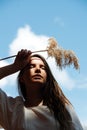 Low angle portrait of a young woman holding fluffs at her forehead