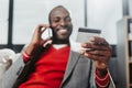 Pleased male with bankcard talking by smartphone