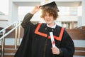 Low angle portrait of happy triumphant male graduate standing near university holding up diploma. From below of young Royalty Free Stock Photo