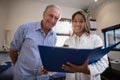 Low angle portrait of smiling senior male patient and female doctor with file Royalty Free Stock Photo