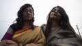 Portrait of two young Indian brunette girls/sisters/friends with traditional wear sari having fun on a rooftop Royalty Free Stock Photo