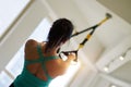 low angle rear view of asian woman doing TRX suspension exercise indoors