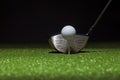 Low angle selective focus of golf ball and driver on a green with black background Royalty Free Stock Photo