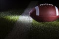 Low angle selective focus view of a football at a yard line with dramatic lighting