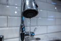 Low angle, selective macro focus on a stainless steel kitchen sink faucet, with water pouring in a thin steady stream Royalty Free Stock Photo