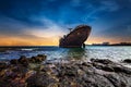 Low-angle shot of an abandoned giant rusty ship near the seashore under the sunset sky.