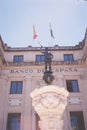 Low angle shot of a beautiful sculpture in front of a concrete building with bank of Spain print