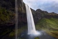 Low angle shot of the beautiful Seljalandsfoss waterfall in Iceland cascading down a mossy cliff
