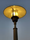 Vintage street lamp glowing yellow against evening sky Royalty Free Stock Photo