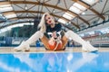 Low angle shot of a blond cheerleader sitting on the floor with a basketball between her legs. Sport concept. Royalty Free Stock Photo