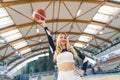 Low angle shot of a blond cheerleader with a stretched arm holding a ball. Sport concept. Royalty Free Stock Photo