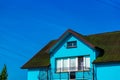 Low angle shot of a blue house with a green rooftop under a clear blue sky Royalty Free Stock Photo