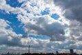 Low angle shot of a bright sky with many clouds with a small fragment of a city below