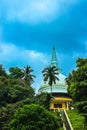 Low angle shot of a Buddhist temple on top of a green hill under a cloudy blue sky in Sri Lanka Royalty Free Stock Photo