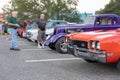 Low angle shot of classic cars and people looking at them.