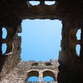 Low angle shot clear blue sky seen inside the ruins of old stone building