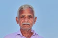Close up face photo of elderly Indian Hindu farmer man with clear blue sky background behind