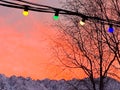 Low angle shot of colorful Christmas lights hanging on a cable on a mountain landscape background