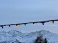 Low angle shot of colorful Christmas lights hanging on a cable on a mountain landscape background