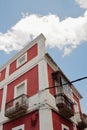 Low angle shot of a facade of a white and red building under a cloudy sky