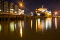 Low angle shot of a huge ship in a river with the reflection of the street lights