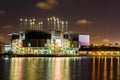 Low angle shot of an industrial building at night with the reflection of the lights in the river Royalty Free Stock Photo