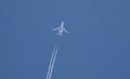 Low angle shot of a jet plane with contrails against a clear blue sky Royalty Free Stock Photo