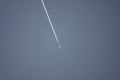 Low angle shot of a jet plane with contrails against a clear blue sky Royalty Free Stock Photo