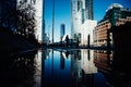 Low angle shot of a man on the street against tall buildings with his reflection on the puddle