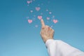 Low angle shot of a man's hand pointing out 3D rendered pink heart icons